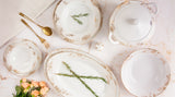 Claudia Radiance porselensservise med gulldetaljer, tallerkener, serveringsfat og suppeterrin sett ovenfra.