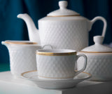 Nærbilde av Sepinood-serviset med kaffekopp og tefat i front, omgitt av tekanne, sukkerskål og sausenebb i hvitt porselen med elegante gulldetaljer