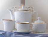 Sepinood kaffeservise i hvitt porselen med elegante gulldetaljer, med kopp og tefat i front, tekanne, sukkerskål og sausenebb.