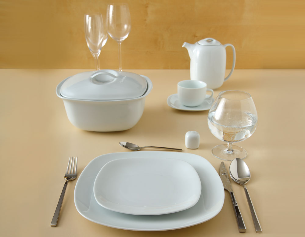 Quattro White porselensservise med firkantede tallerkener, suppeterrin, tekanne og kopp i en moderne borddekking.
