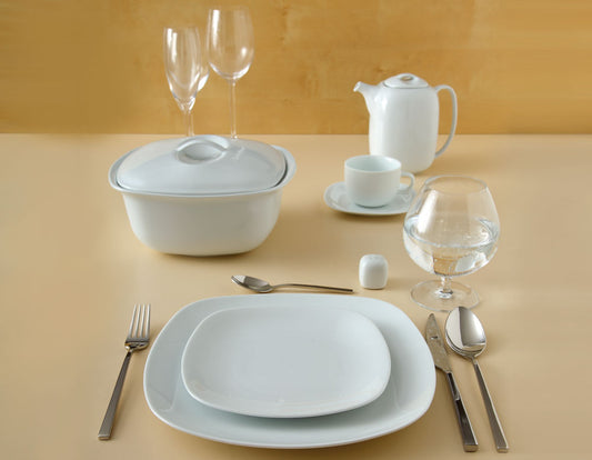 Quattro White porselensservise med firkantede tallerkener, suppeterrin, tekanne og kopp i en moderne borddekking.