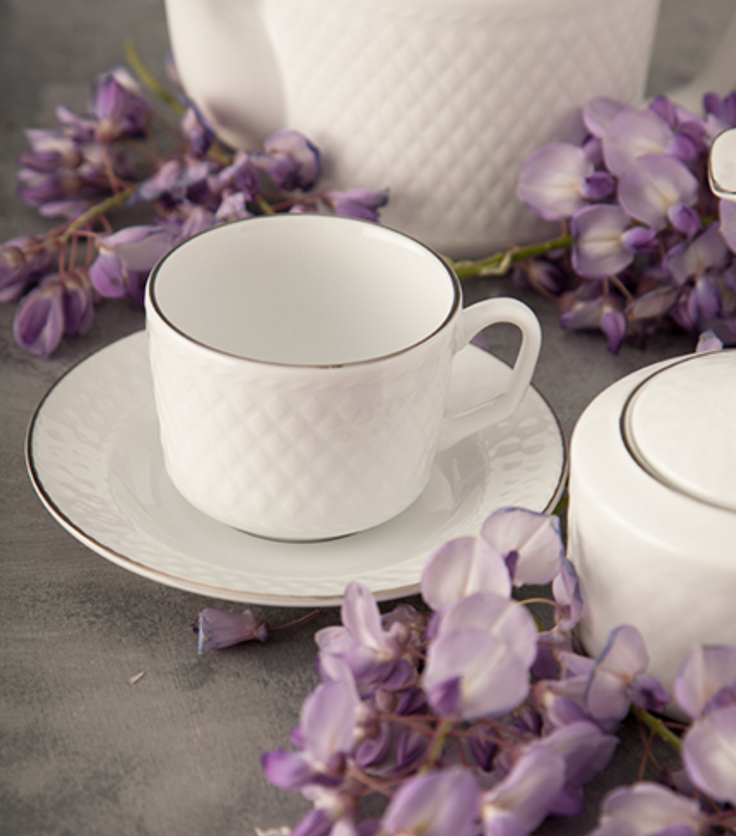 Tekanne, sukkerskål, fløtemugge og kopp fra Radiance Silver-serviset med diskret relieff og sølvfarget kant.