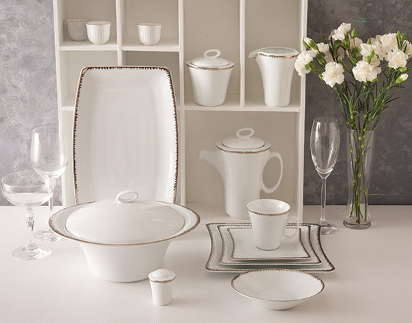 Royal-serviset med serveringsdeler i hvitt porselen med elegante platinadetaljer, inkludert suppeterrin, tekanne, serveringsfat, kopper og skåler.